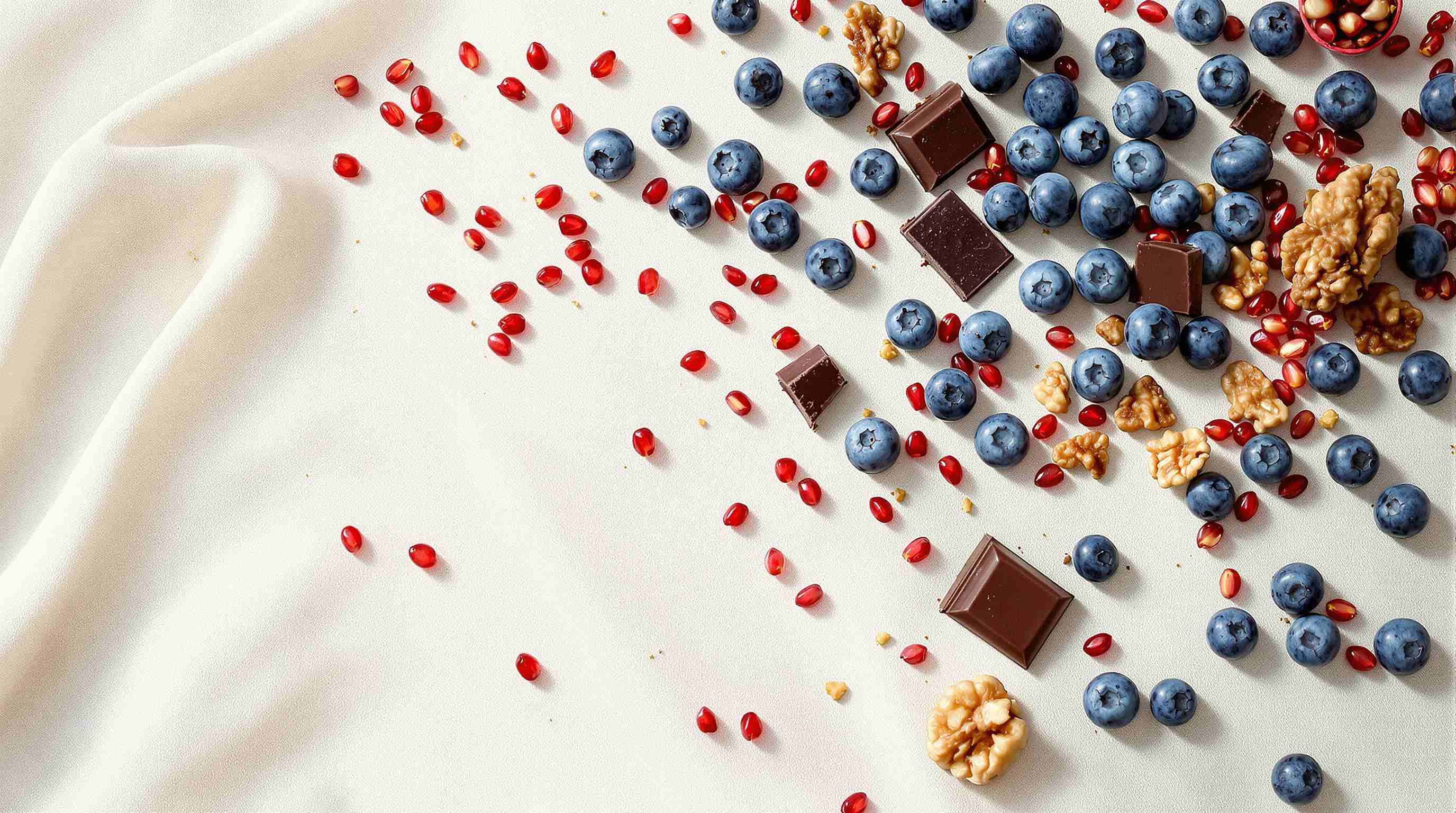 Frische Beeren, Nüsse und dunkle Schokolade auf einem Holzbrett, Draufsicht